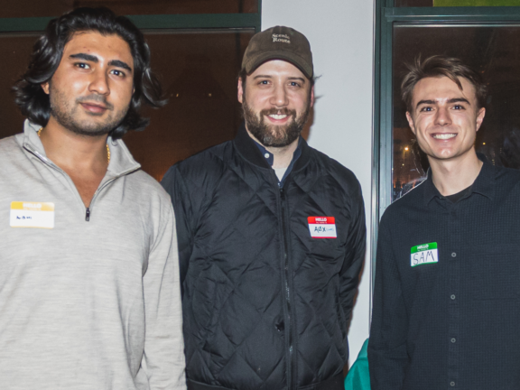 Three attendees posing with name tags at an indoor event