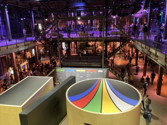 Overhead view of a busy industrial-style event venue with colorful booth display