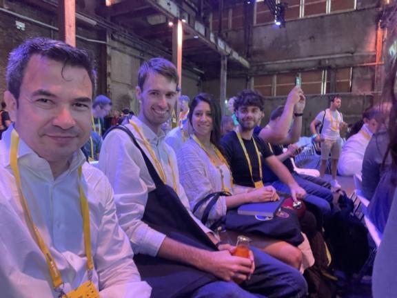 Conference attendees seated in a row wearing yellow lanyards