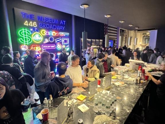 Crowded bar event under neon signs at The Museum at 446 Broadway