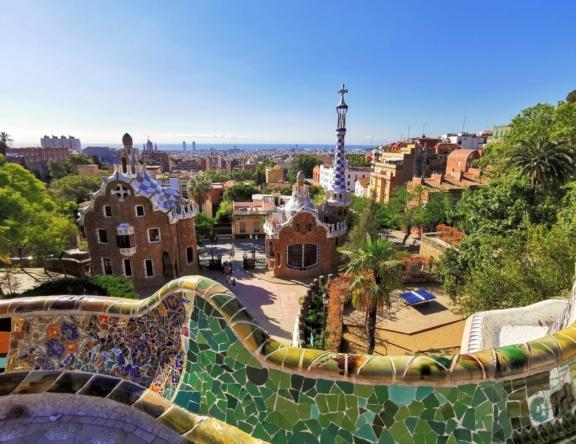 View over Park Gell in Barcelona with mosaic railing, buildings, trees, and city skyline