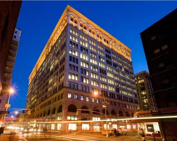 Illuminated city building at dusk with traffic light trails
