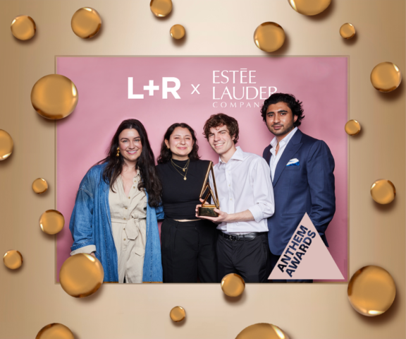 Group of four holding a trophy in front of L+R and Este Lauder Companies backdrop