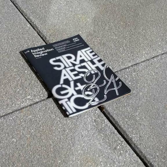Black typographic booklet lying on a concrete floor