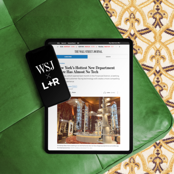 WSJ and L+R phone beside tablet showing a Wall Street Journal article on a green sofa
