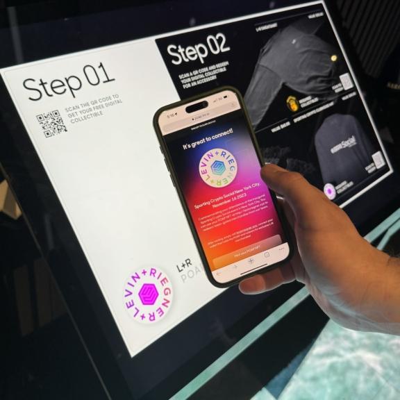 Hand holding phone in front of a step-by-step event check-in screen