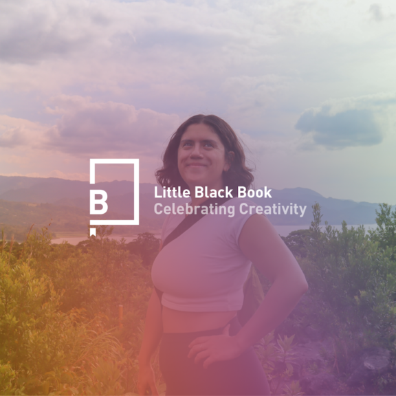 Person posing on a hilltop with Little Black Book logo over a colorful sky and mountain landscape