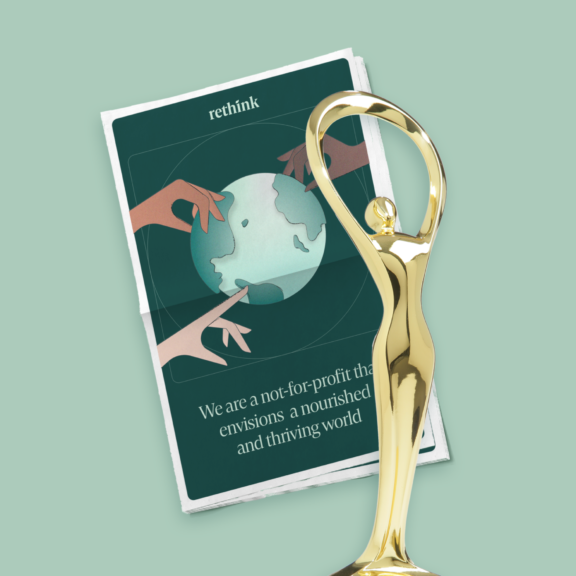 Gold trophy standing over a Rethink brochure on a pale green background.