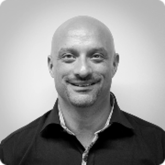 Jay wampold Black-and-white headshot of a smiling bald man in a dark collared shirt