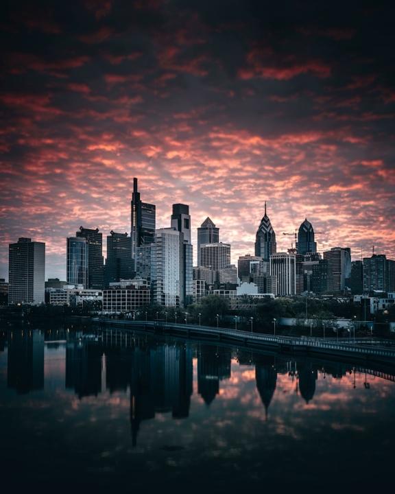 City skyline at sunset reflected in a river under dramatic pink clouds