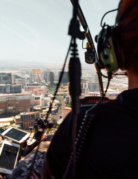 Helicopter passenger wearing headset overlooking a city skyline from above