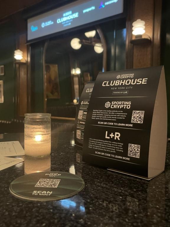 Sporting Crypto Clubhouse table signs with QR codes beside a candle