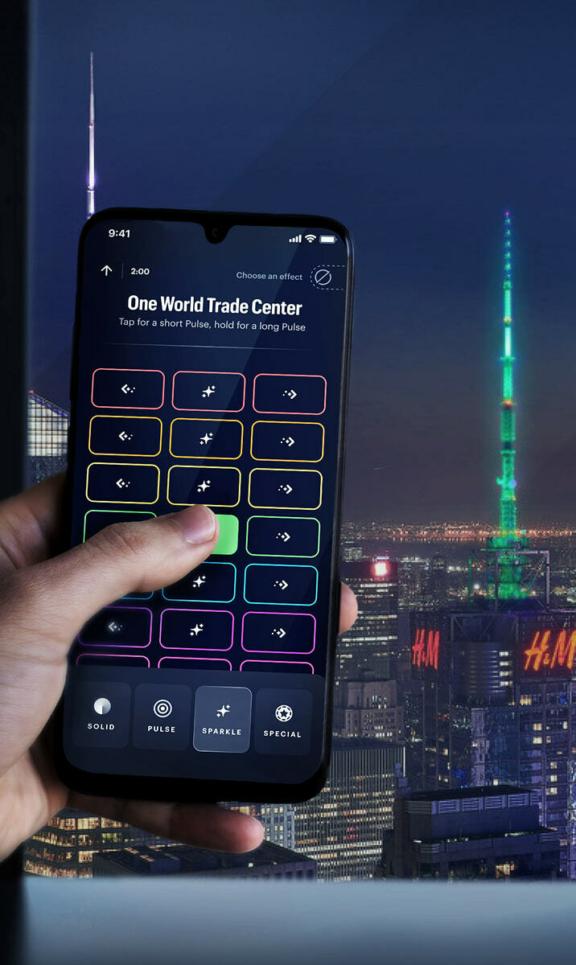 Spireworks2 0 M Cover Hand holding a smartphone lighting control app against a nighttime New York skyline