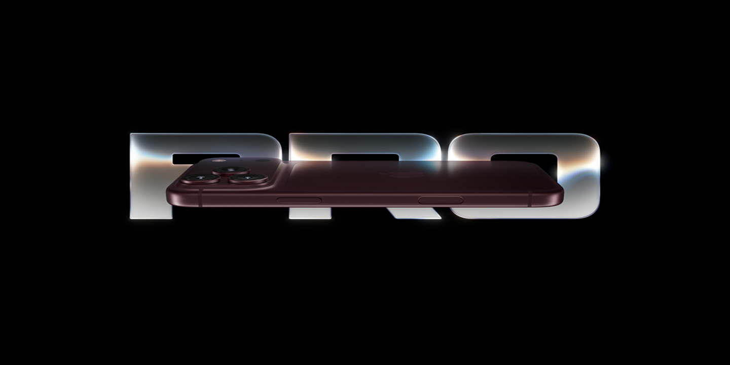 iPhone Pro device shown in front of illuminated Pro lettering on a black background.