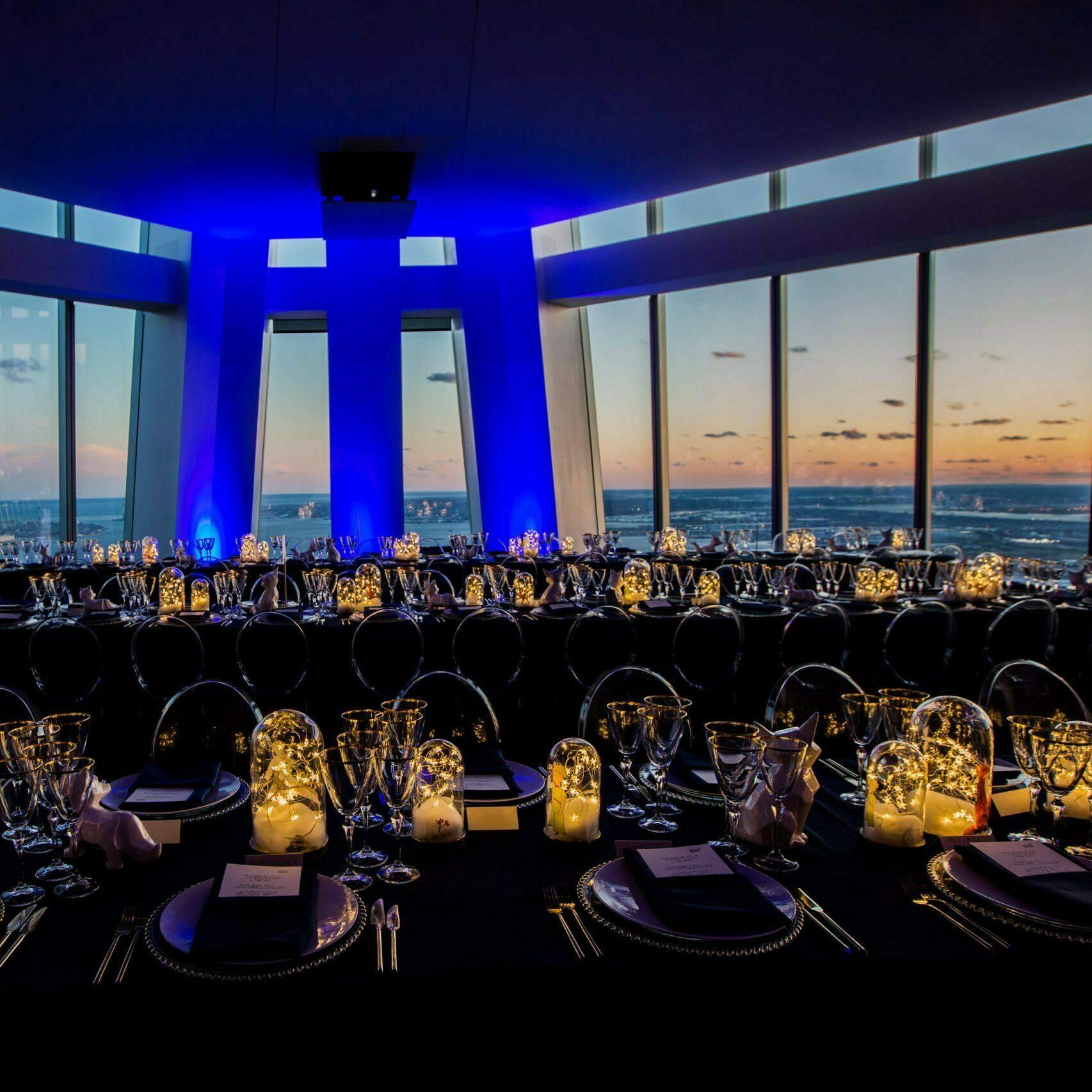 Elegant banquet tables in a high-rise room with city views at sunset