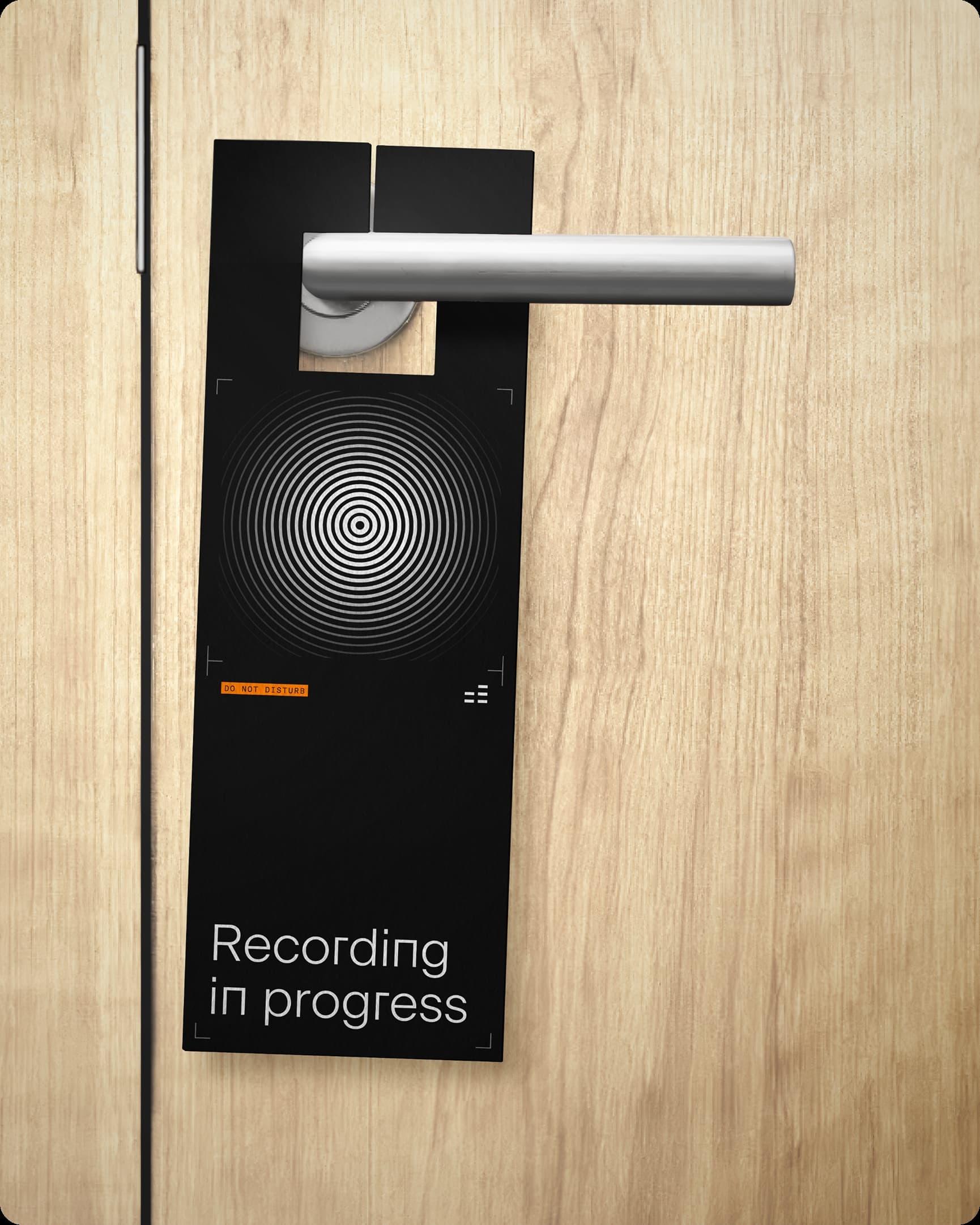 Black "Recording in progress" door hanger on a wooden door handle.