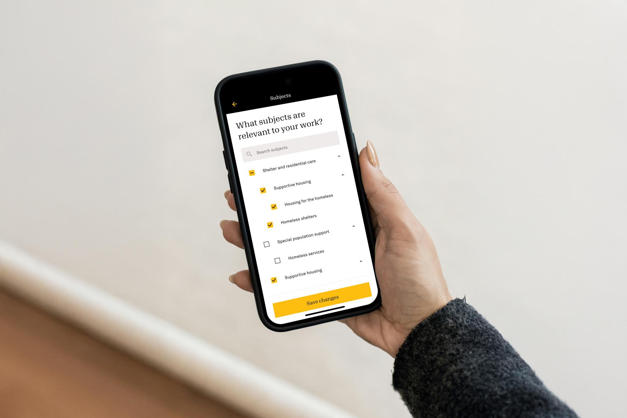 Hand holding phone with subject preference settings screen