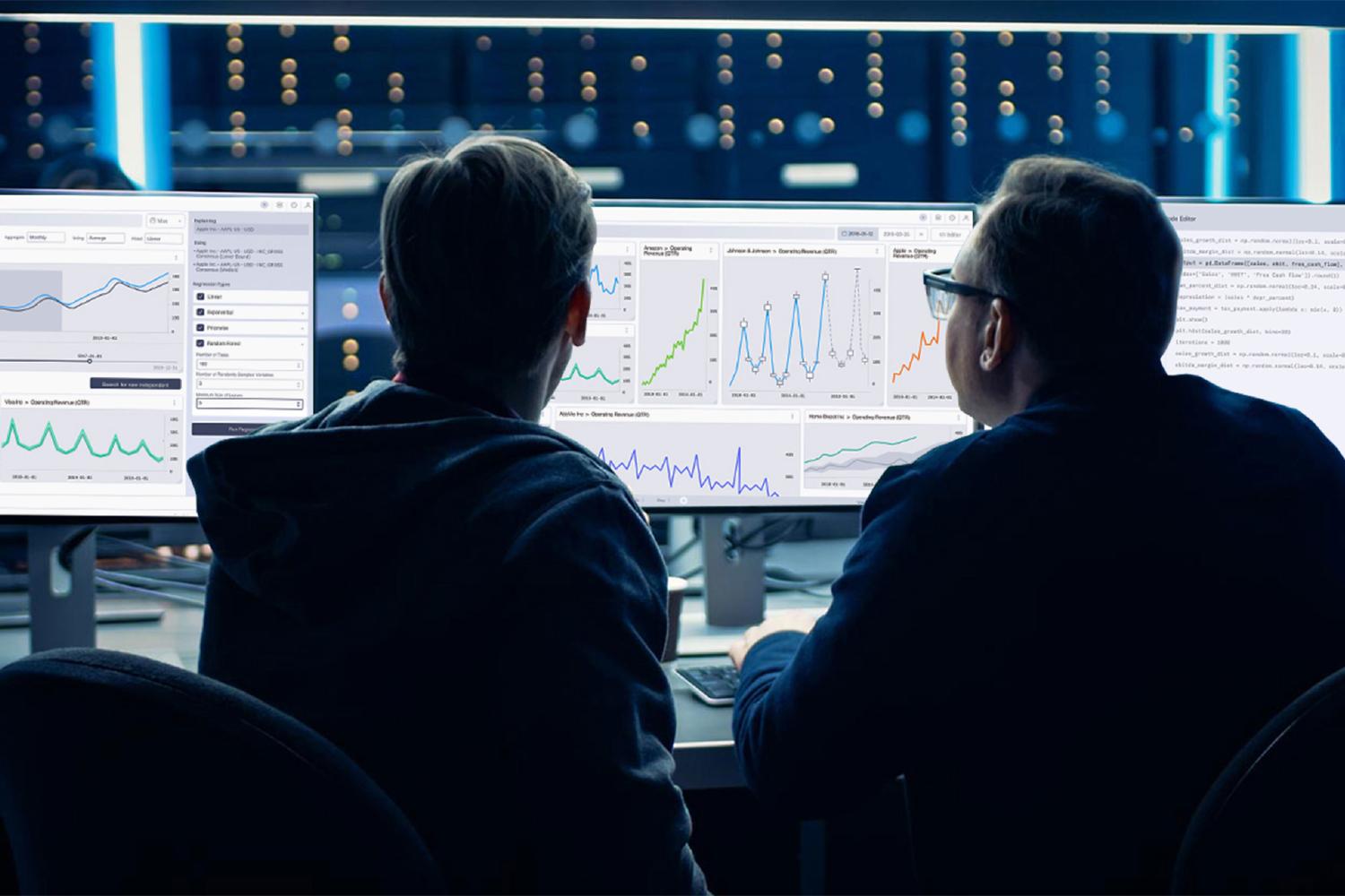 Two people analyzing data dashboards across multiple monitors