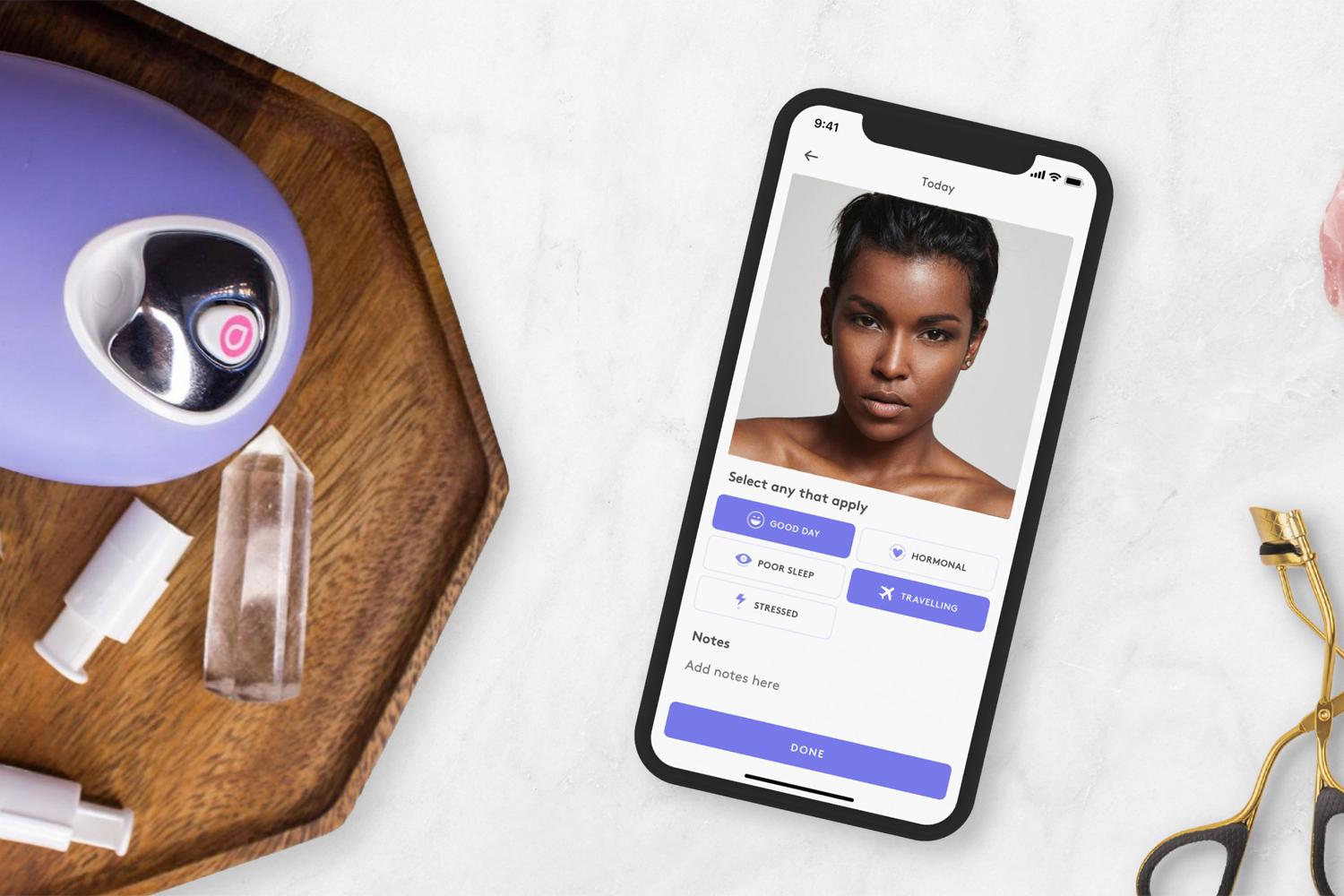 Skincare tracking app on a phone with beauty tools and a Droplette device nearby