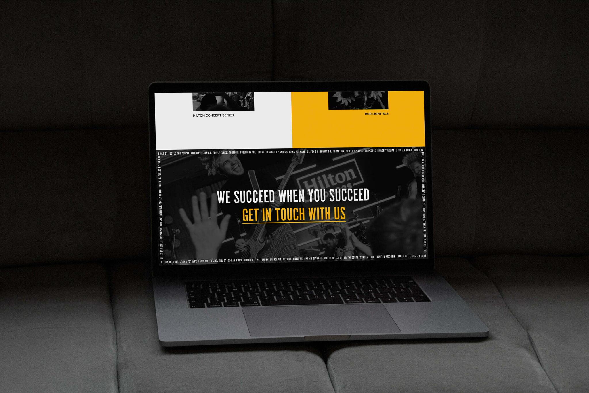 Laptop on a couch showing a website with the headline "We succeed when you succeed"
