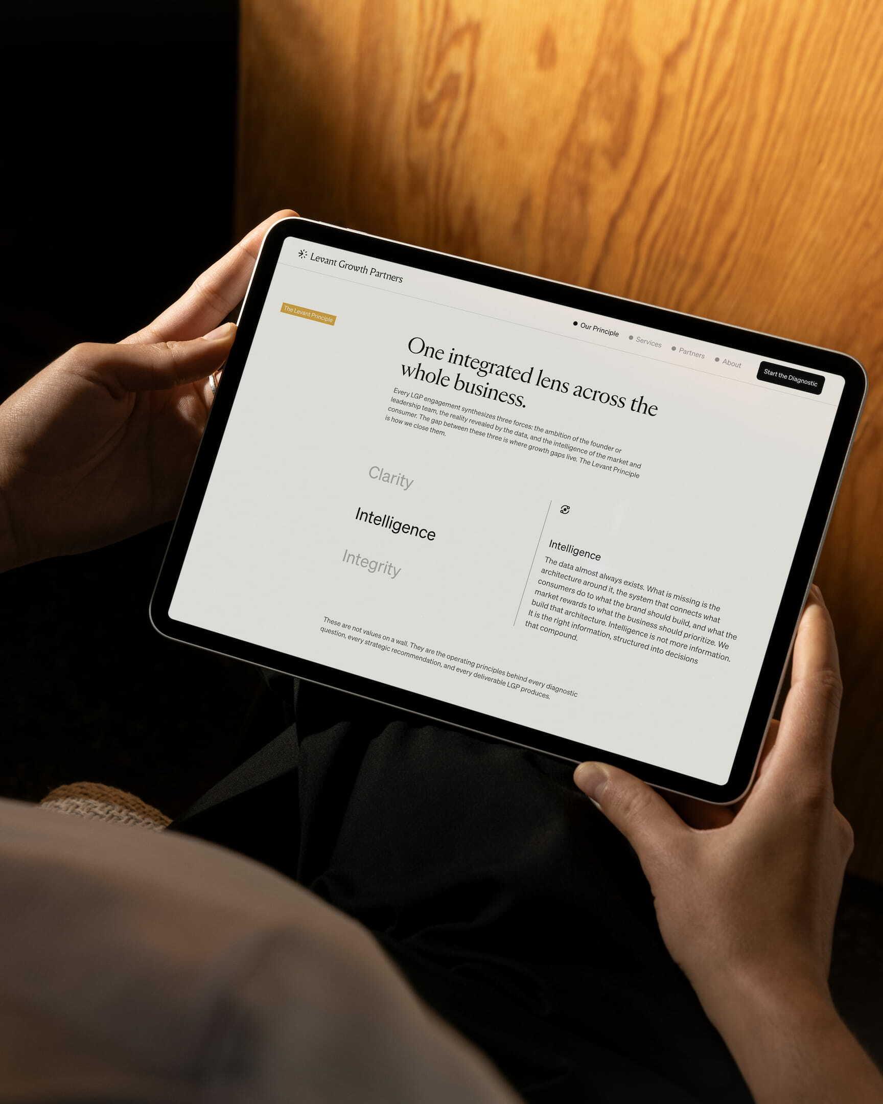 Hands holding a tablet displaying the Levant Growth Partners website