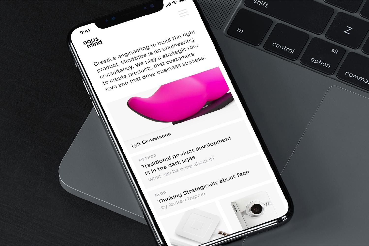 Angled phone on laptop showing a product design consultancy website