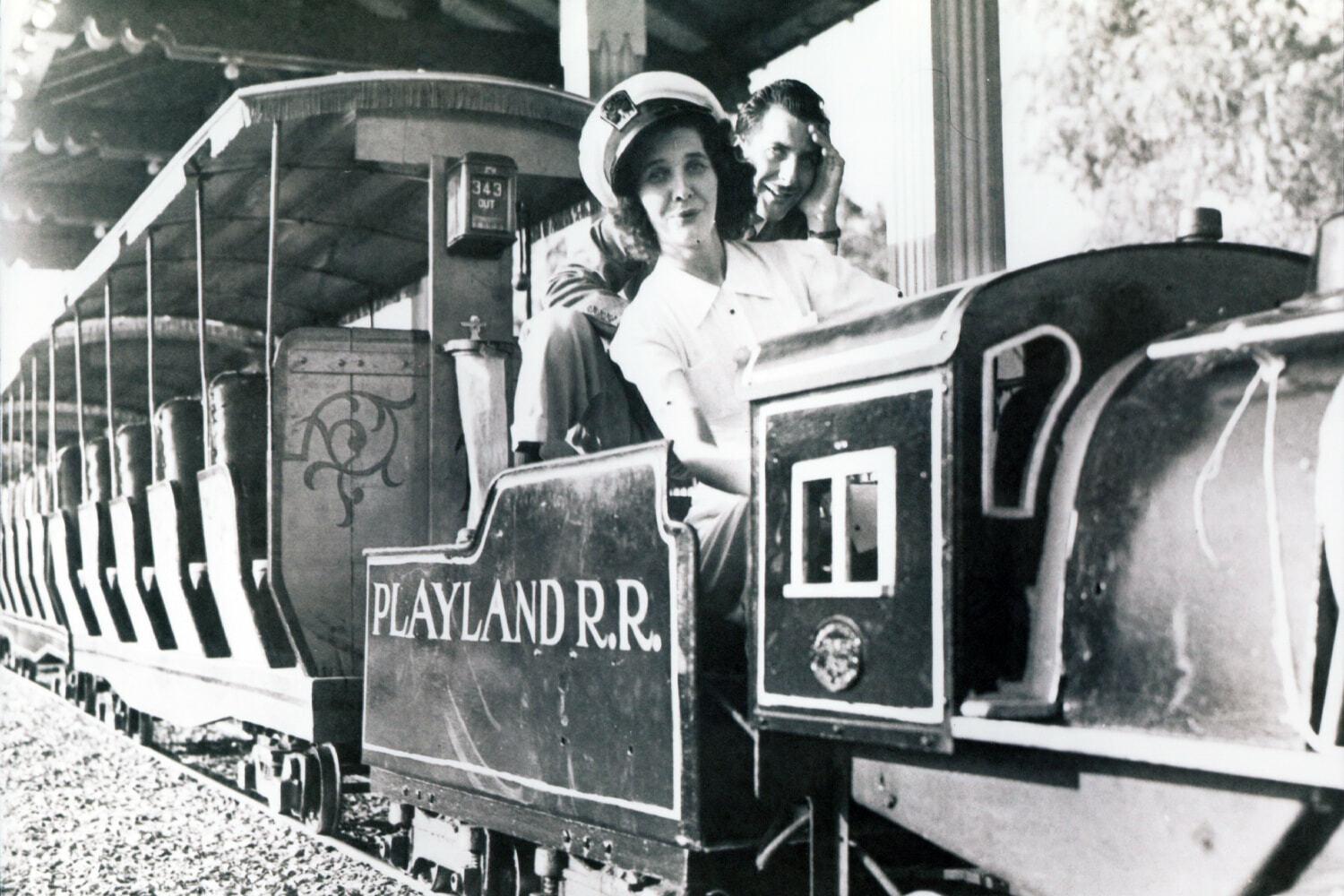 Black-and-white Playland R.R. miniature train with riders at the front