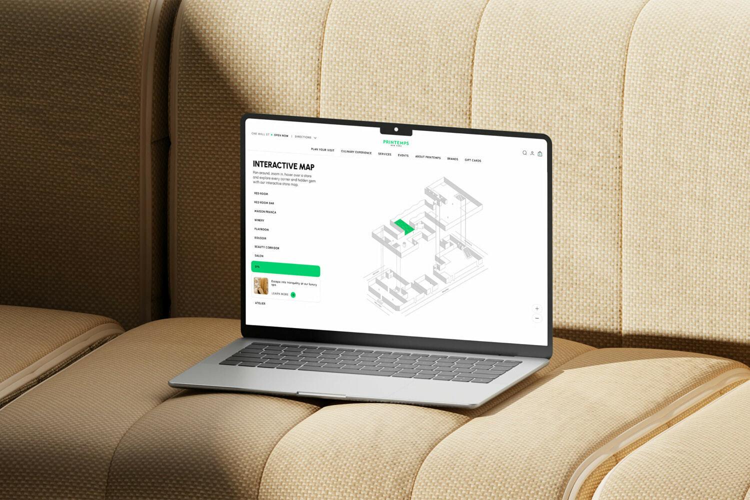 Laptop on a beige upholstered couch displaying an interactive map webpage