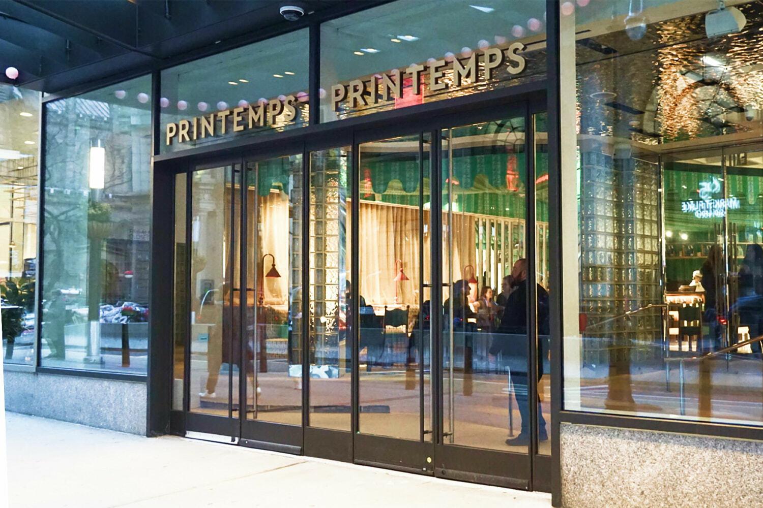 Wide view of Printemps storefront with glass doors and interior caf seating