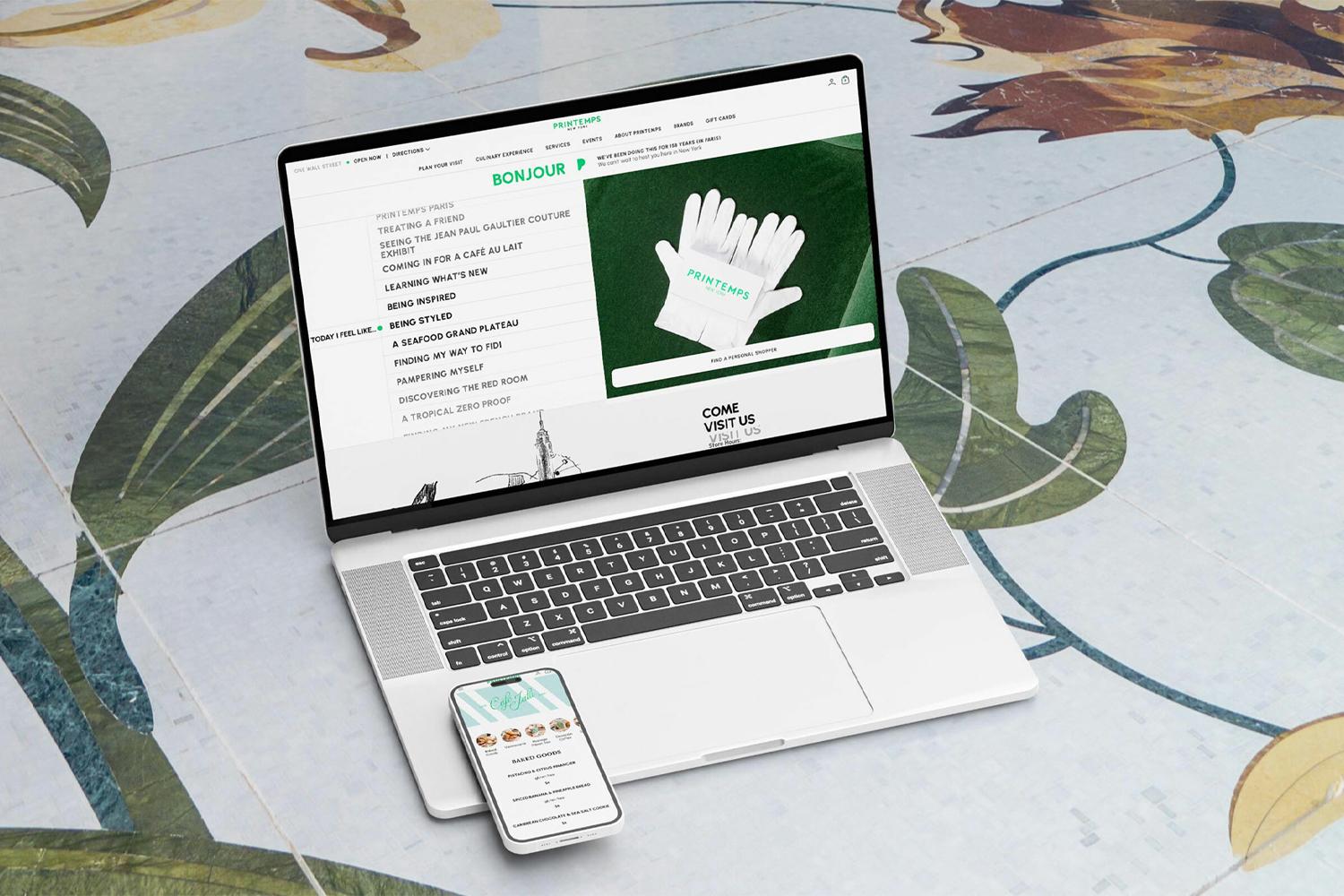 Laptop and phone showing Printemps website on a floral patterned floor