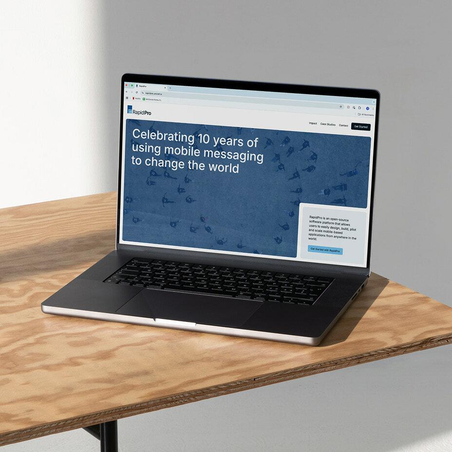Laptop on a wooden table showing a RapidPro anniversary webpage.