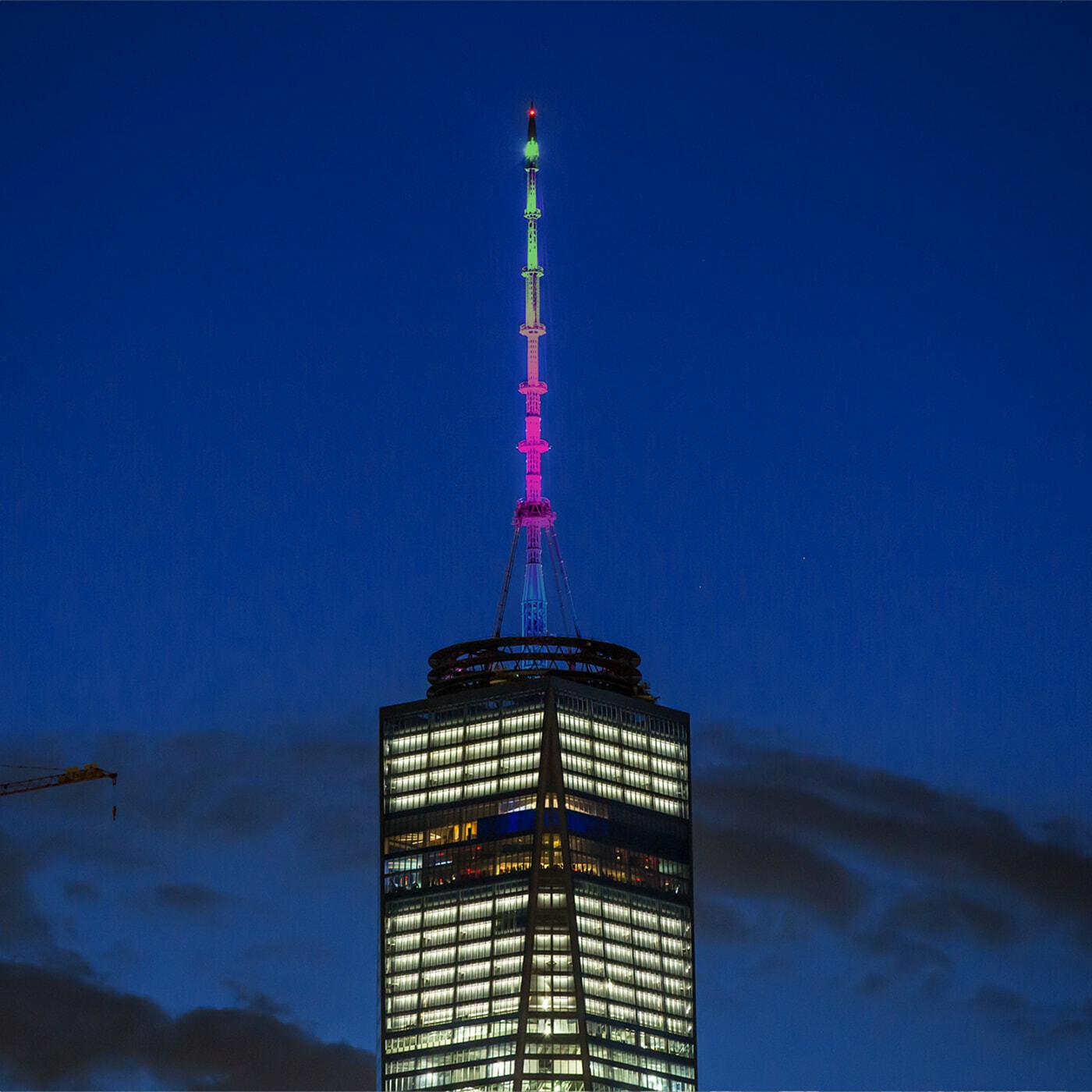 One World Trade Center antenna lit in rainbow colors at dusk