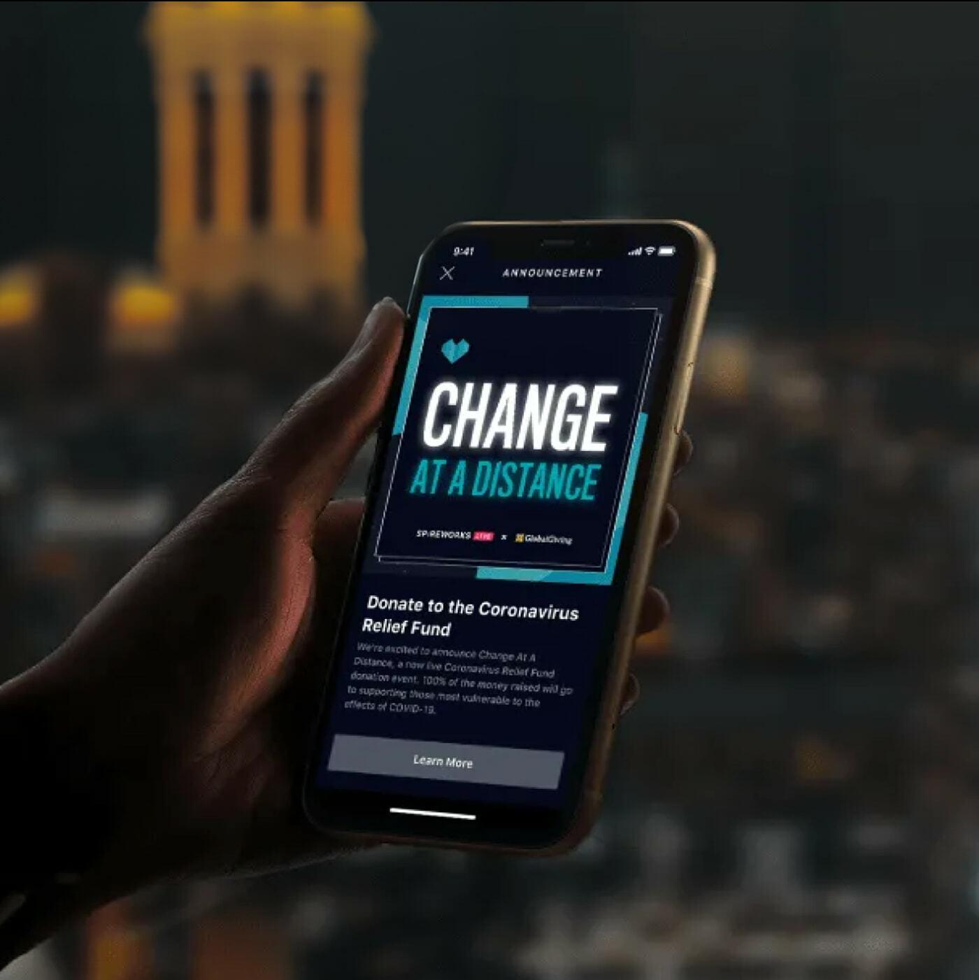 Hand holding a phone showing a Change at a Distance relief fund announcement