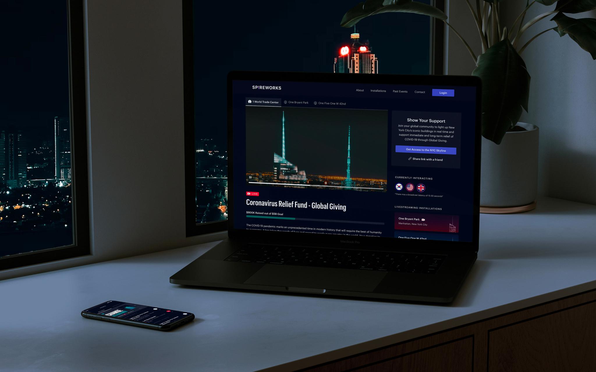 Laptop on a table showing a Global Giving page beside a nighttime city window