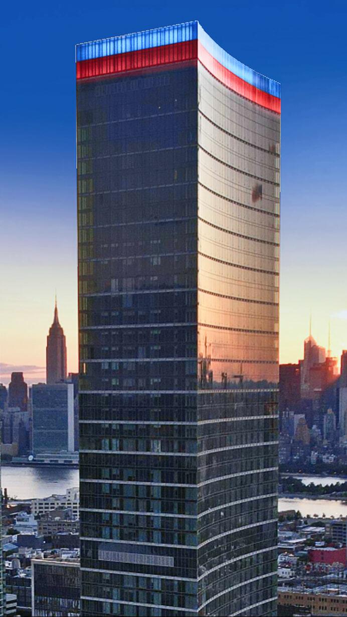 Skyscraper at sunset with red, white, and blue lighting along the top edge