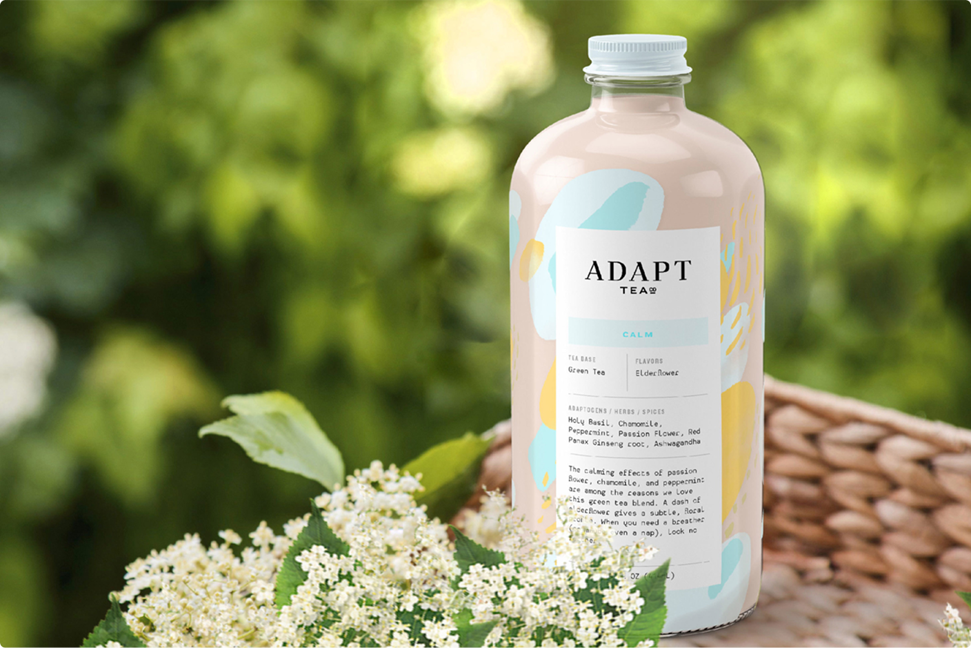 Adapt Tea Calm bottle on a wicker basket with flowers and blurred green background