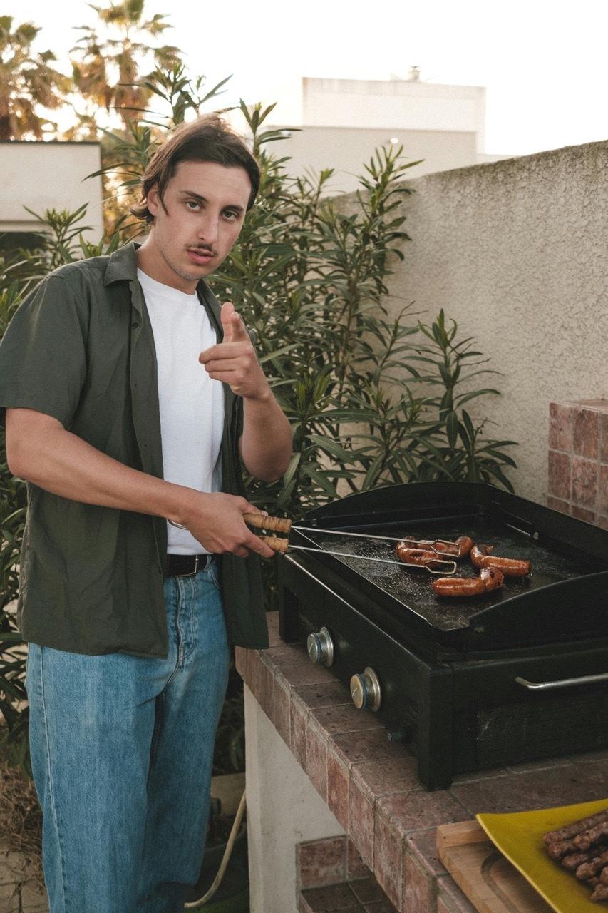 Man grilling sausages on an outdoor patio.