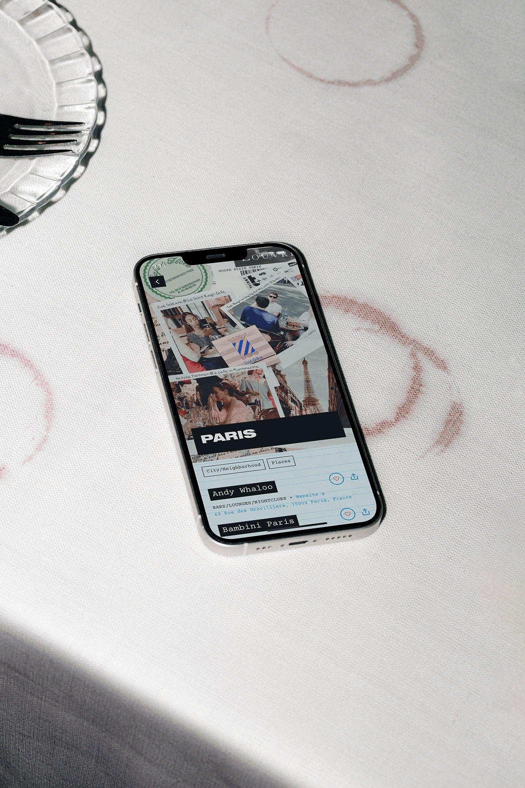 Phone on a table showing a Paris guide page in an app