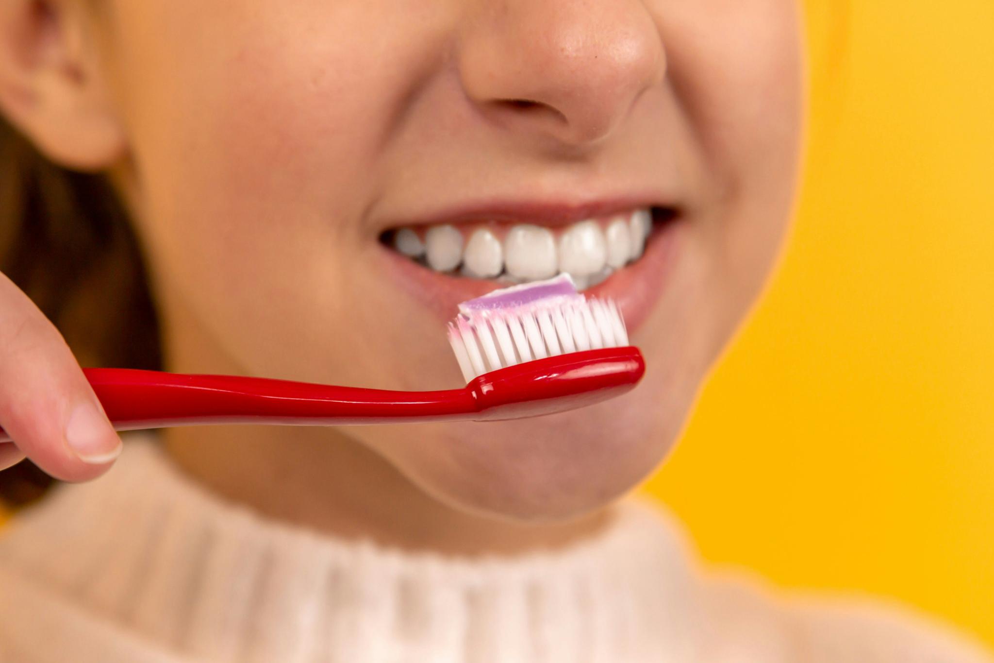 Close-up of a person brushing teeth with a red toothbrush