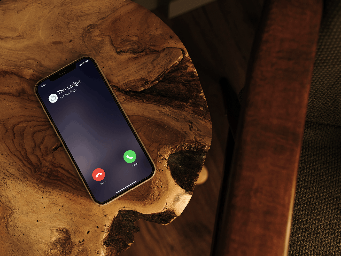 Smartphone with The Lodge incoming call beside a chair on a wood table