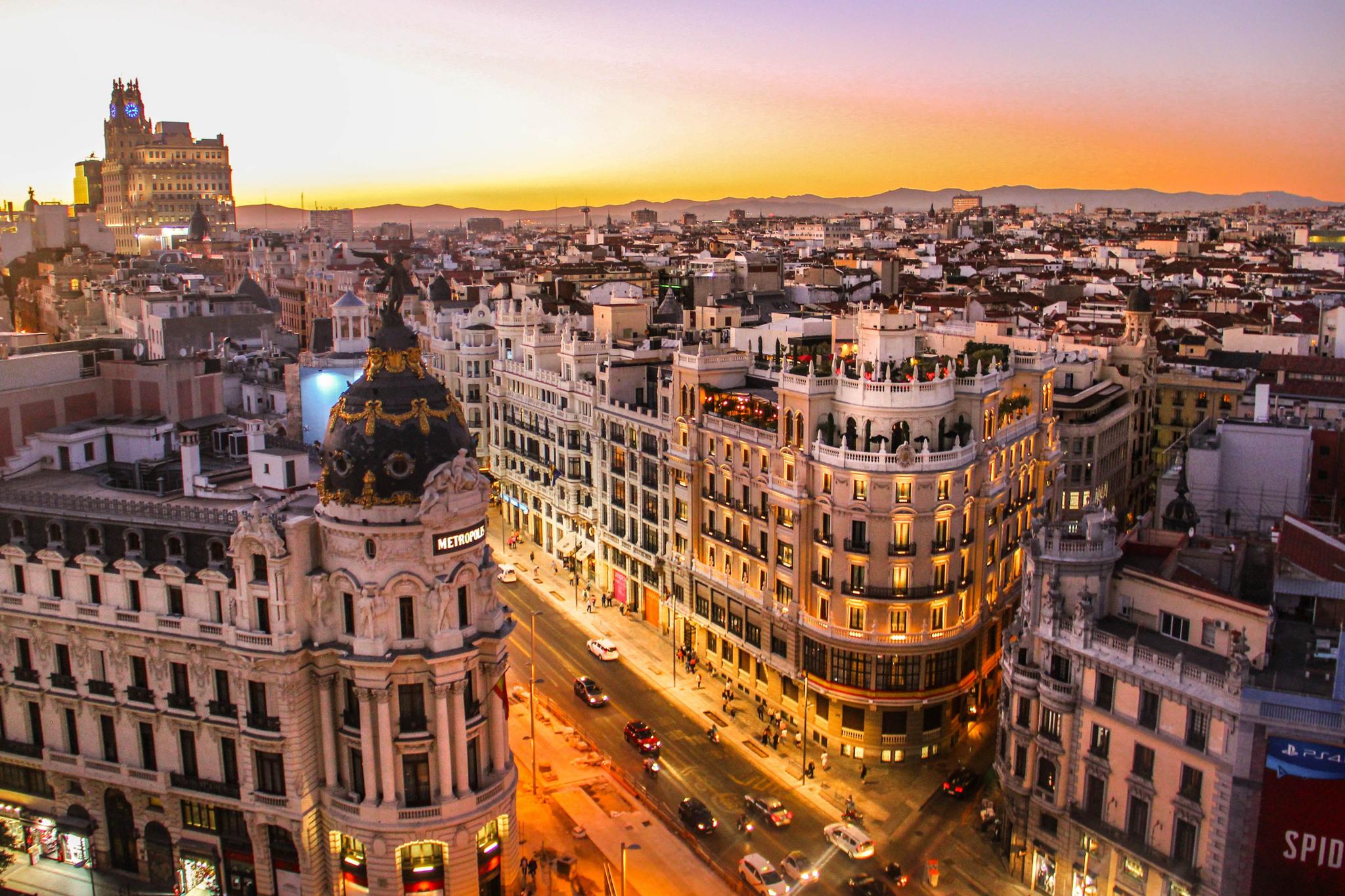 Sunset city skyline with ornate buildings and busy illuminated streets