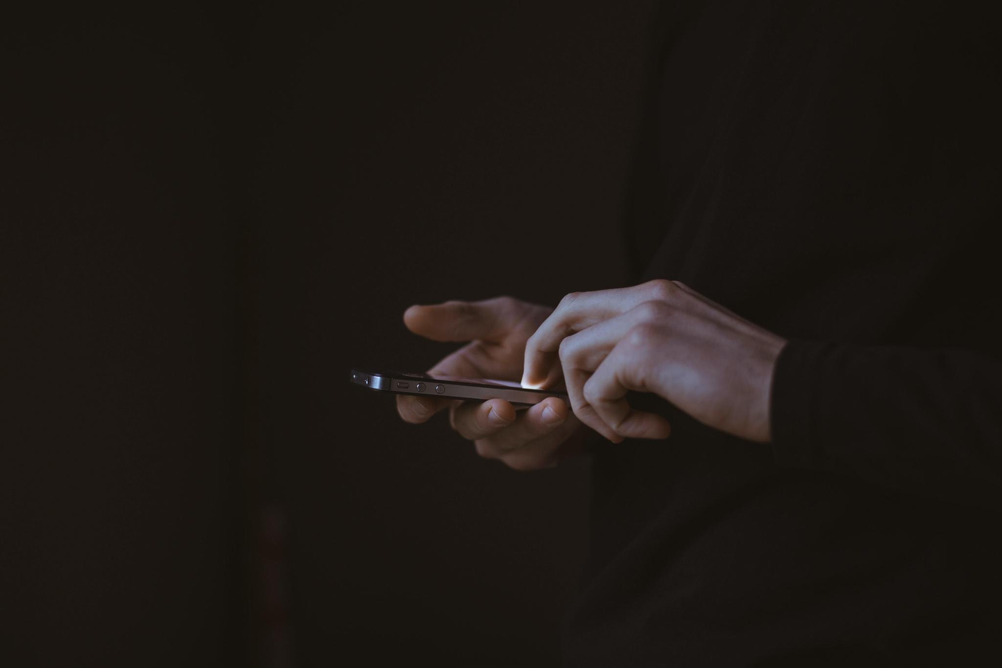 Hands using a smartphone in a dark setting