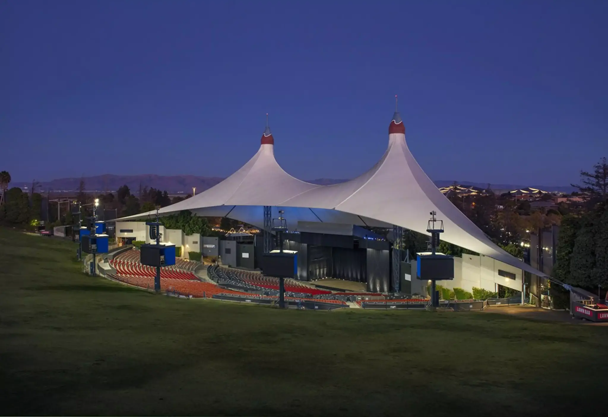 Outdoor amphitheater with white tent-like roof at dusk
