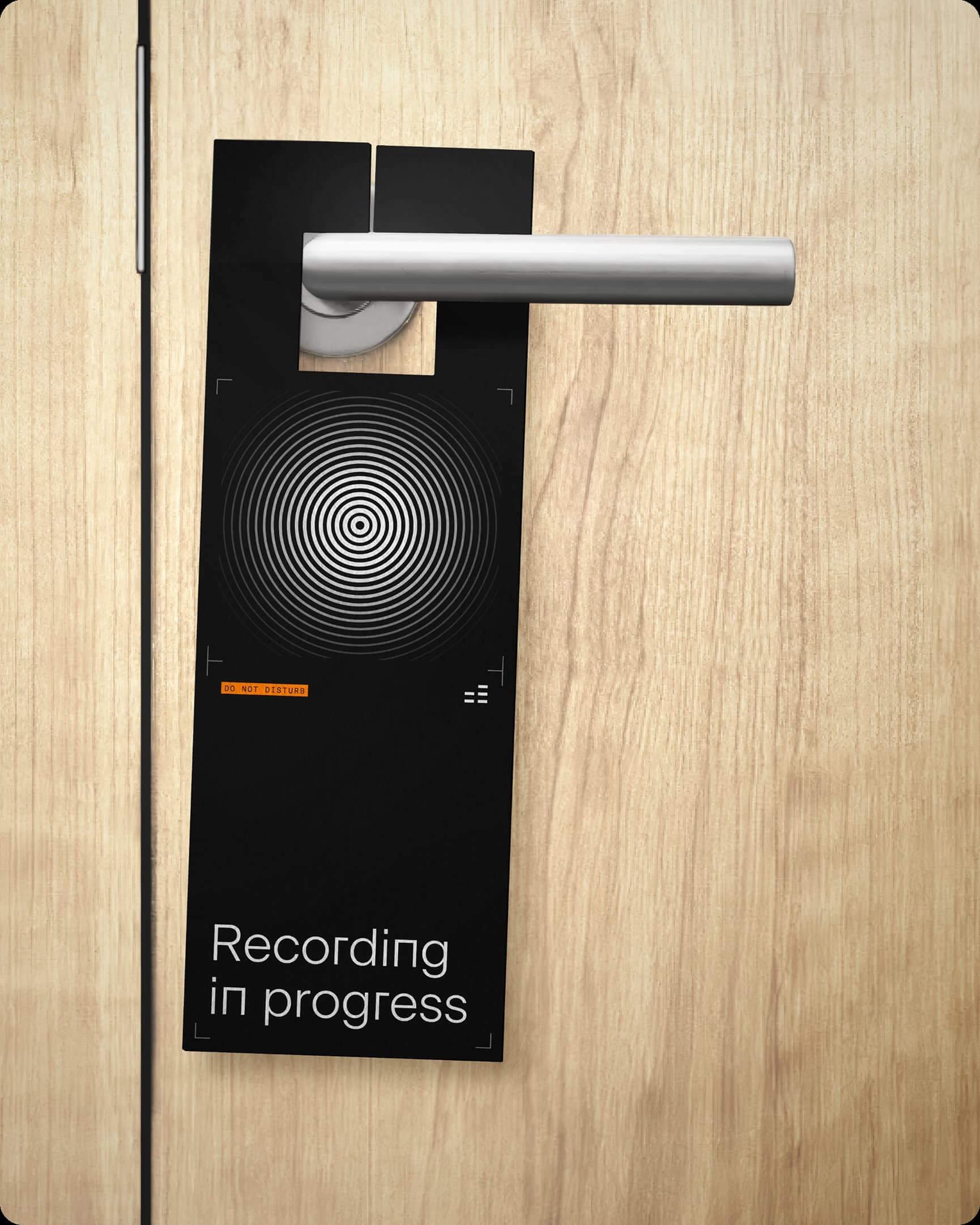 Door hanger on a wood door reading "Recording in progress" with a circular sound pattern