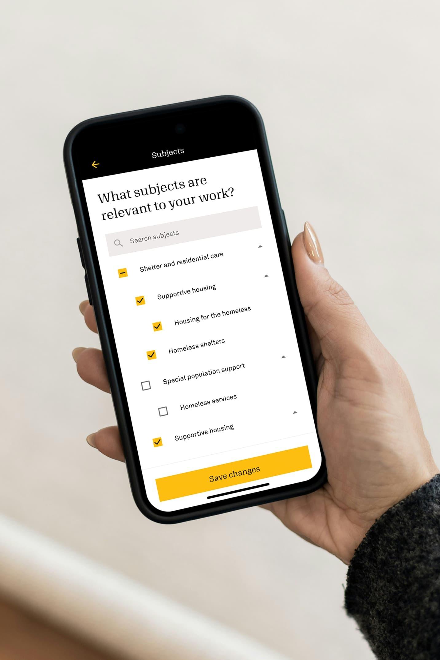 Hand holding phone showing subject preference checkboxes