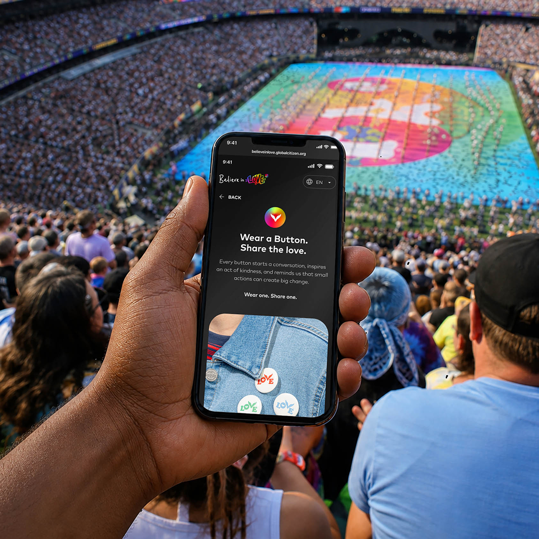 Hand holding a phone in a stadium with a colorful field display below.