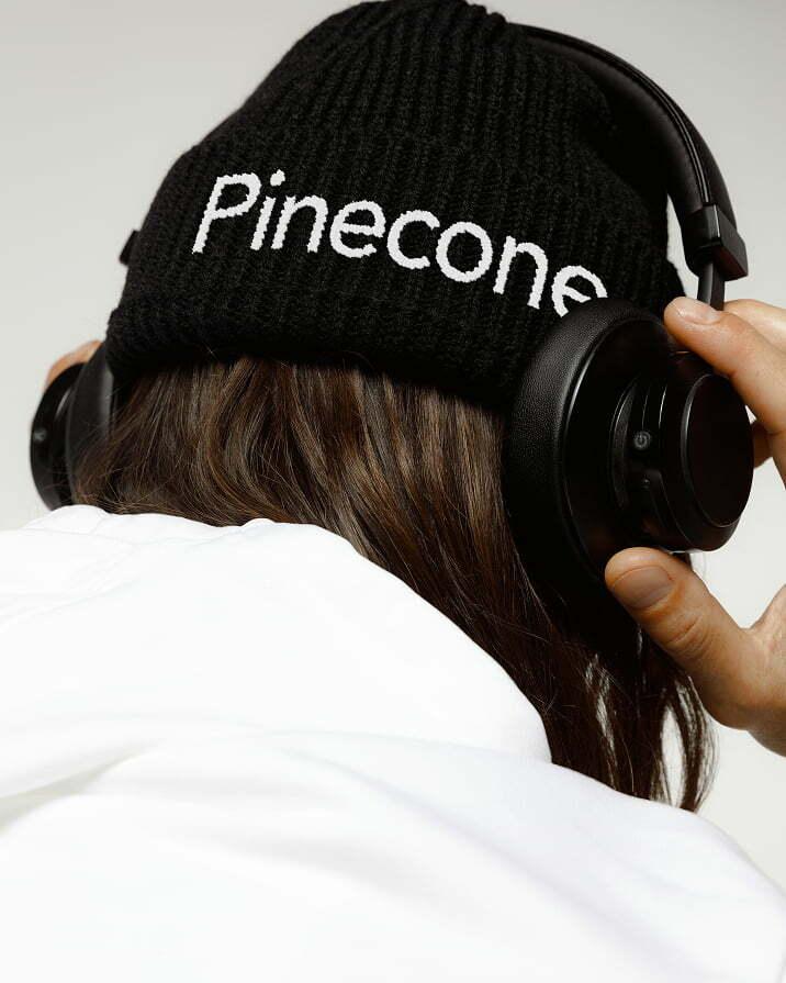 Person wearing headphones and a black Pinecone beanie
