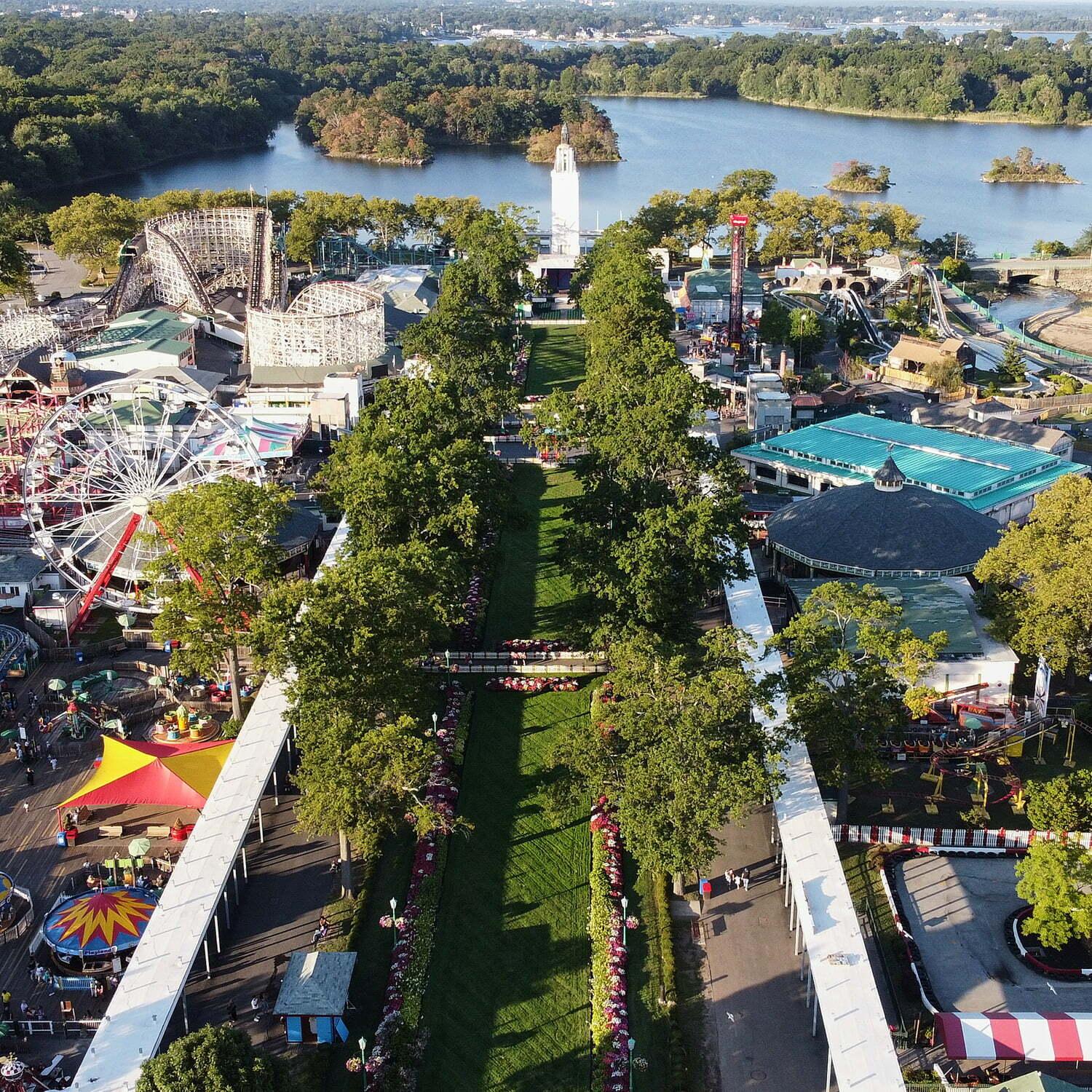 Aerial view of an amusement park beside a lake with rides and trees