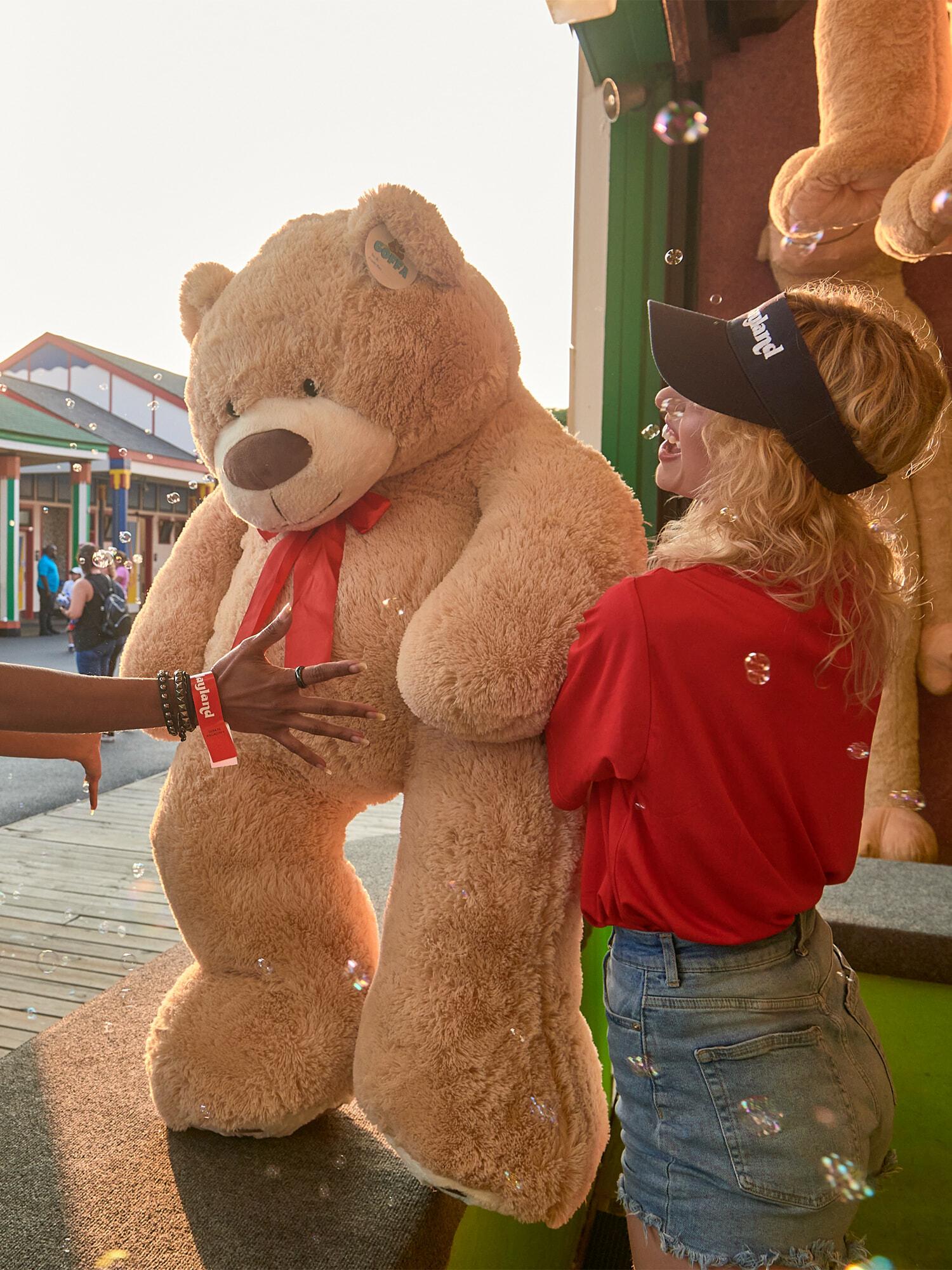 Oversized teddy bear prize at an amusement park game booth with bubbles