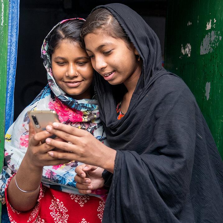 Two girls looking at a smartphone together.